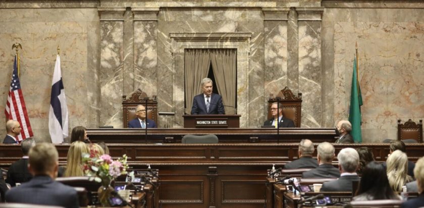 Sauli Niinistö, President of Finland, addresses joint session of Washington State Legislature, Olympia. First foreign head of state to do so in their 134 year history. Governor Jay Inslee seated behind on left. Finnish flag to left. March 6, 2023