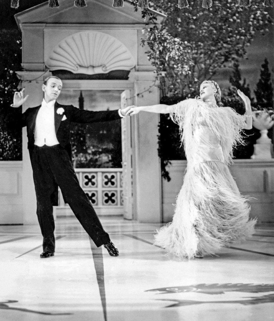 Black and white photo. Fred Astaire, Ginger Rogers (in feathered dress), elegantly dancing in the movie, Top Hat, 1935